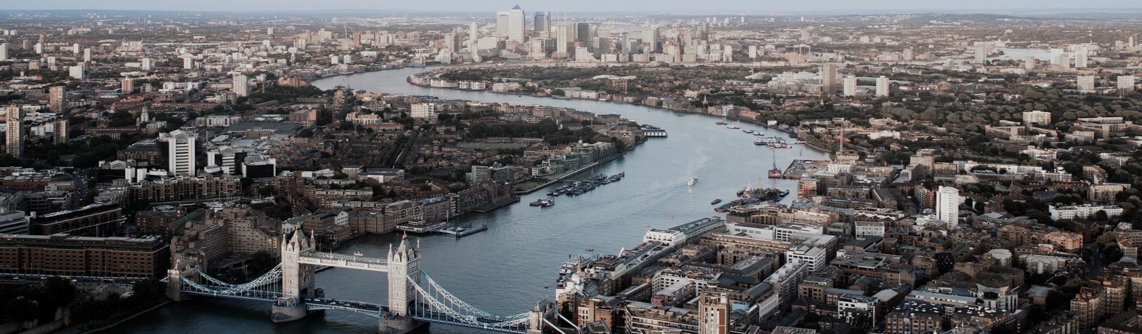 Aerial image of London, displaying the River Thames and Tower Bridge, with the city's skyline in the background.